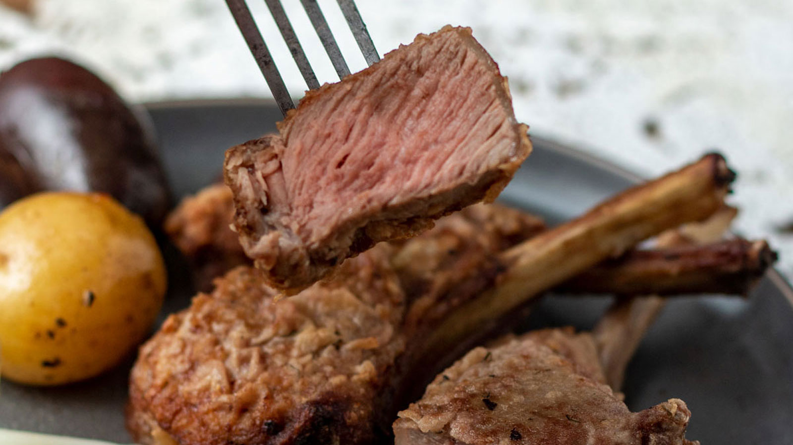 Fork pickling up a slice of medium rare lamb.
