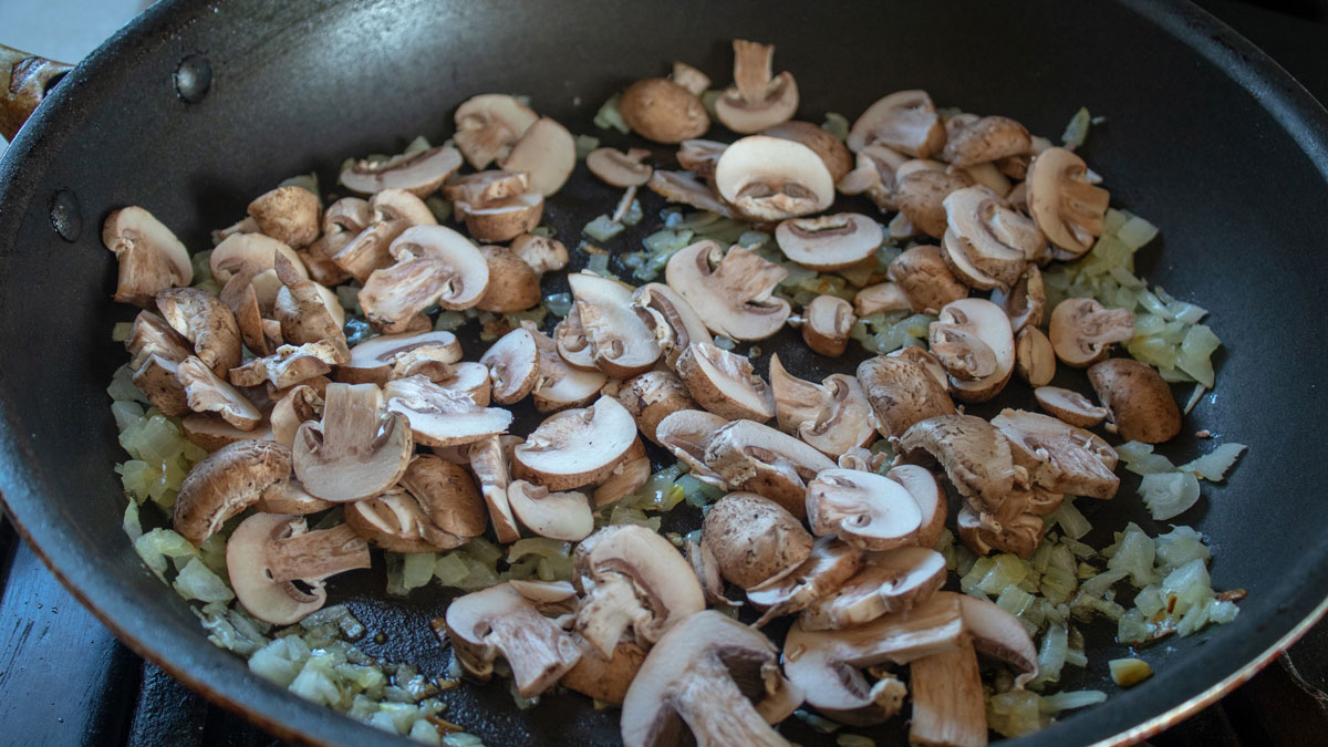 Sliced mushrooms added to the onions in the skillet.