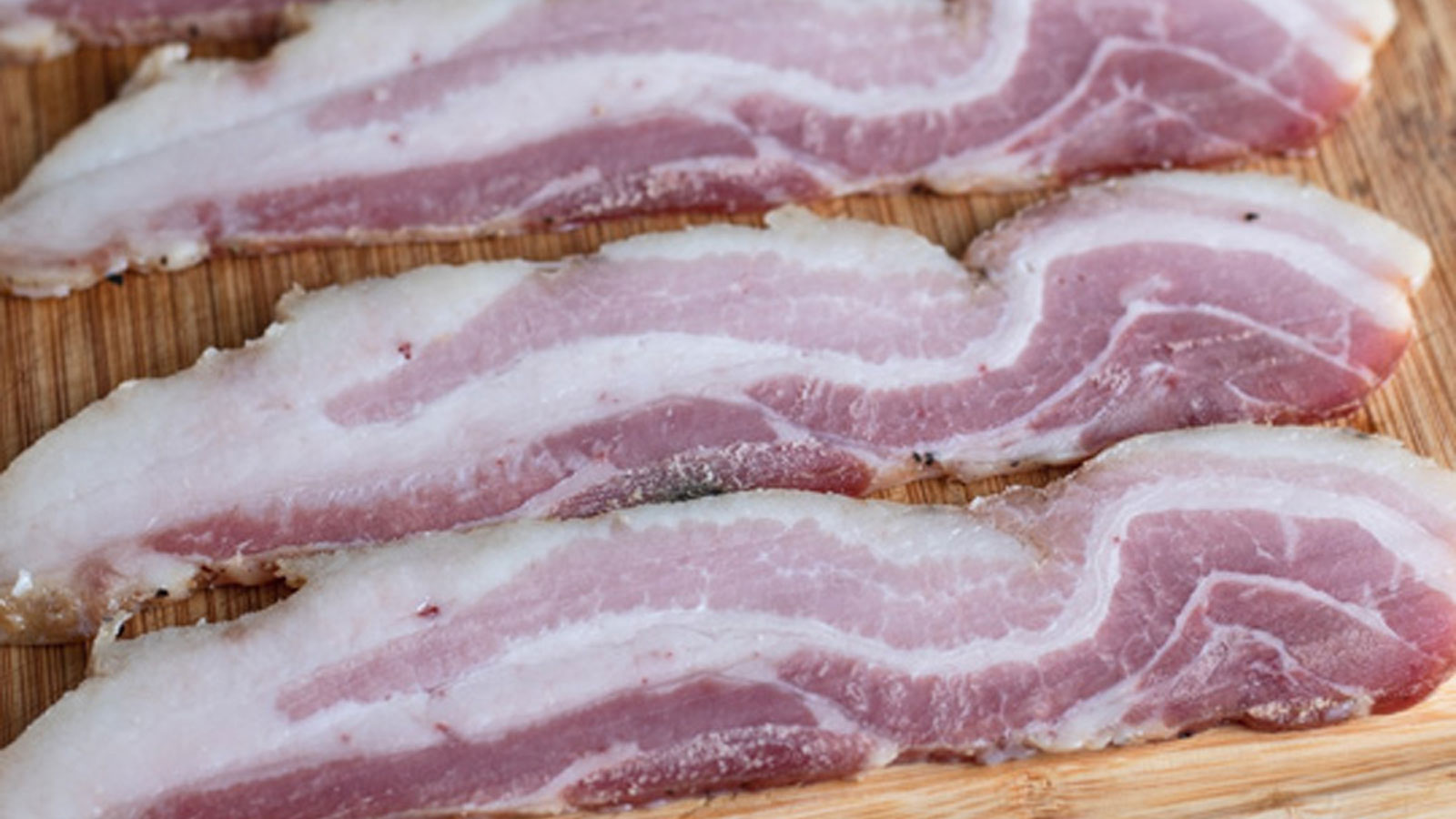 Curing bacons on a wooden board.