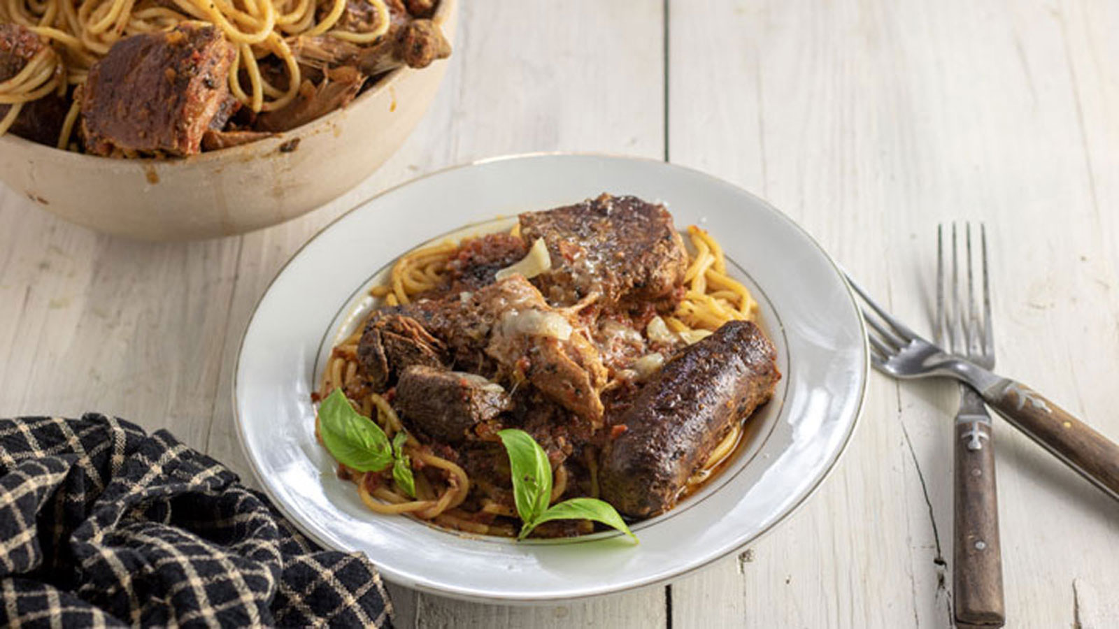 White plate with pasta and meaty pasta sauce.