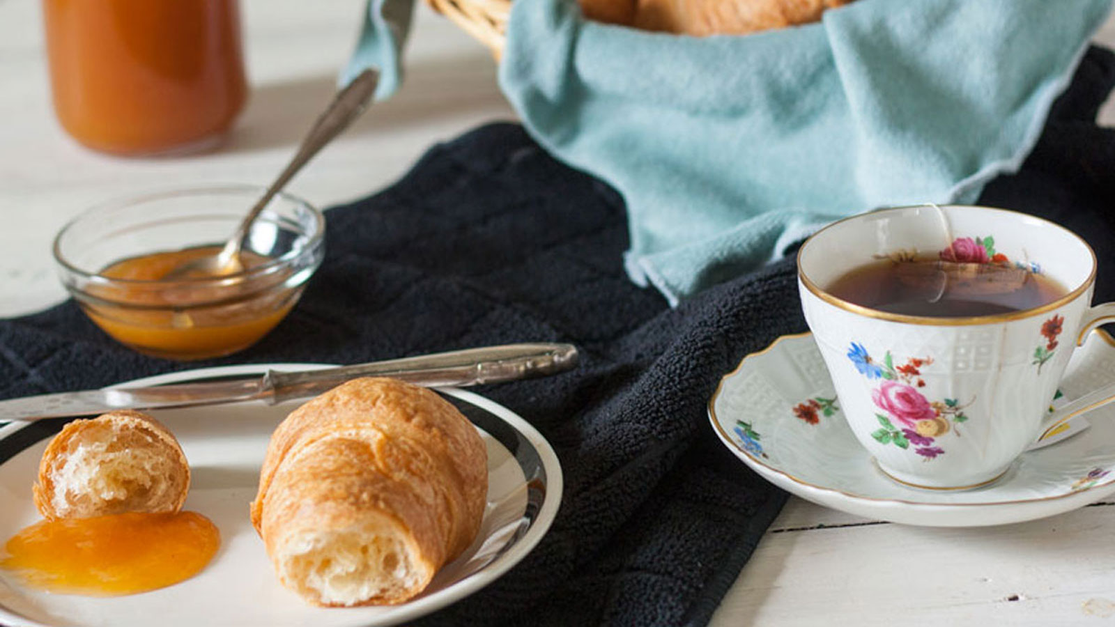 Peach jam on a plate with croissant on the side.