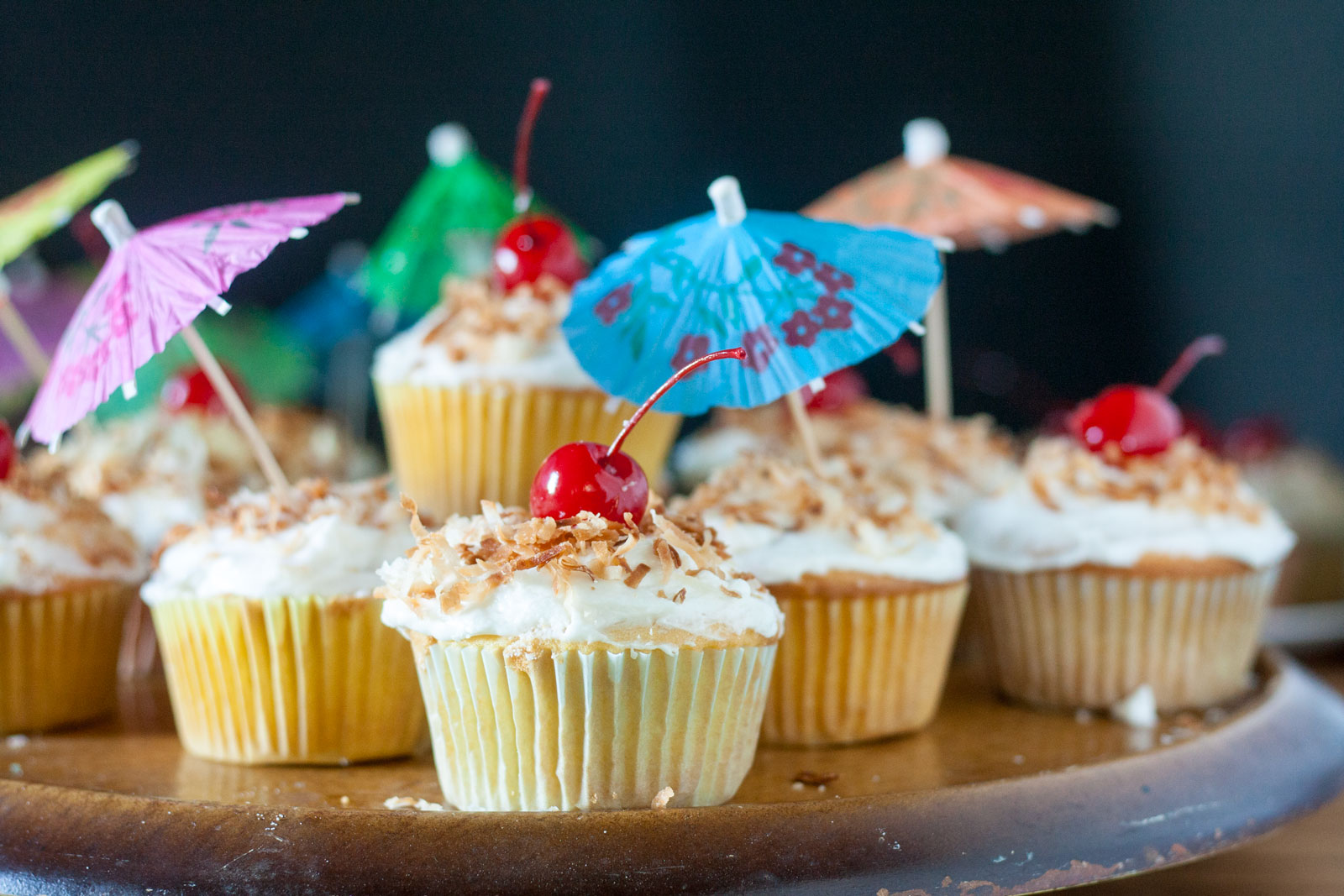 Pina colada cupcakes stacked on a pedestal cake plate.