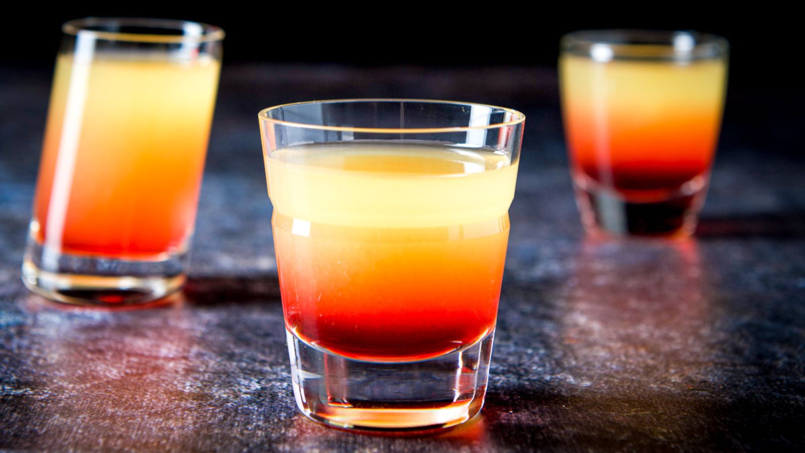 Three shot glasses of pineapple upside down.