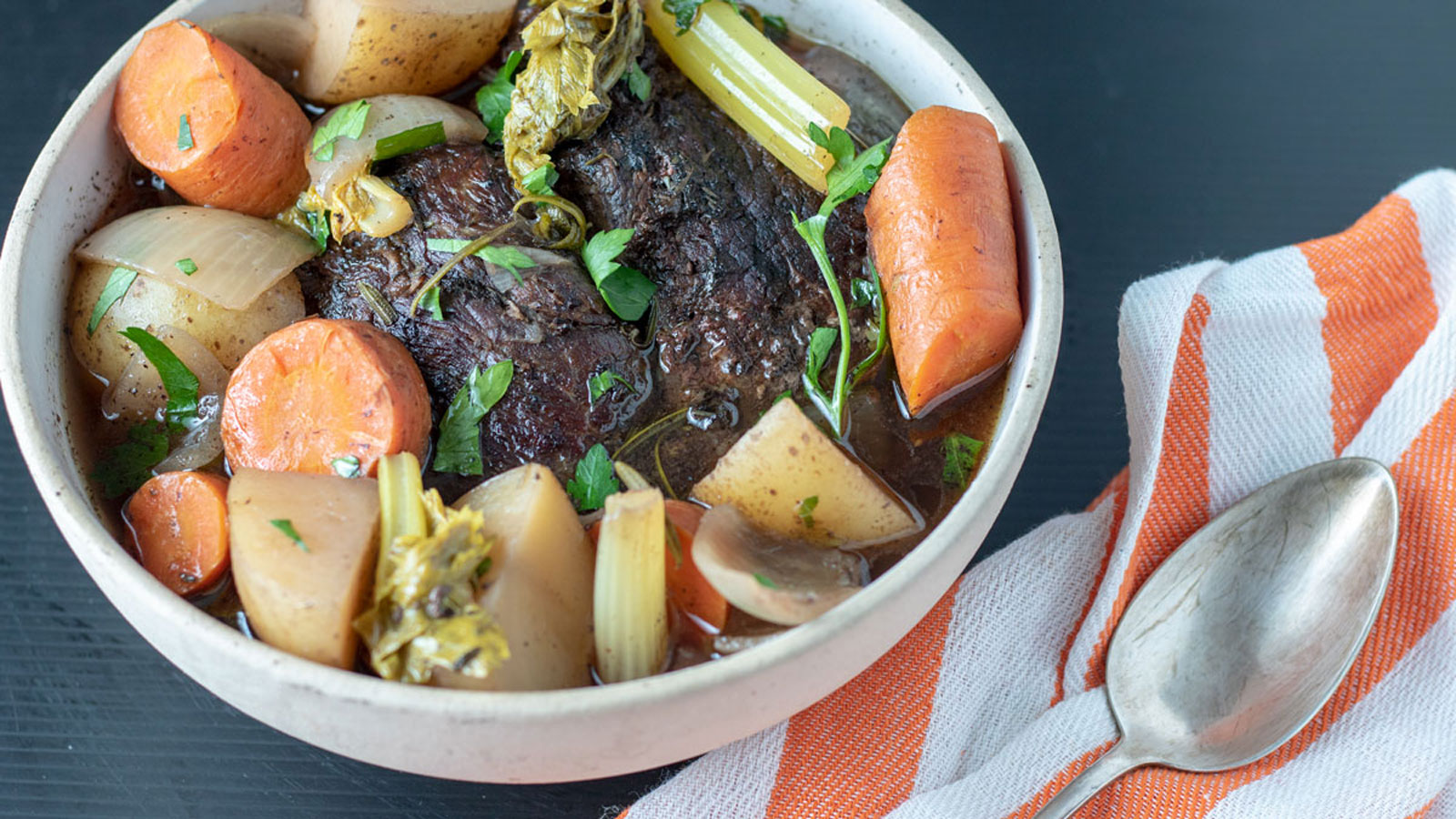 Beef in a bowl with carrots and potatoes.