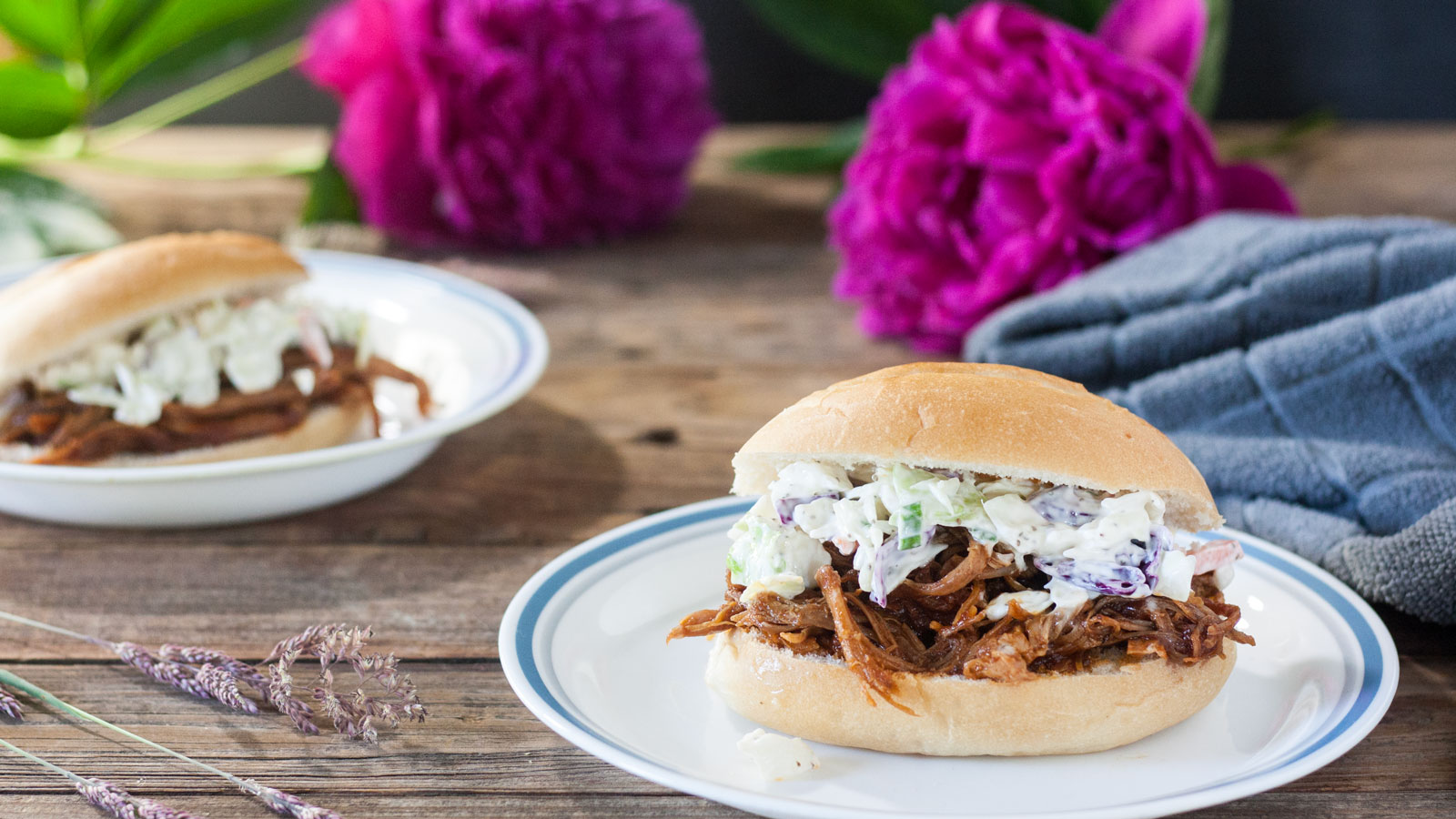 Smoked Pulled pork sandwiches on white plates, topped with cole slaw