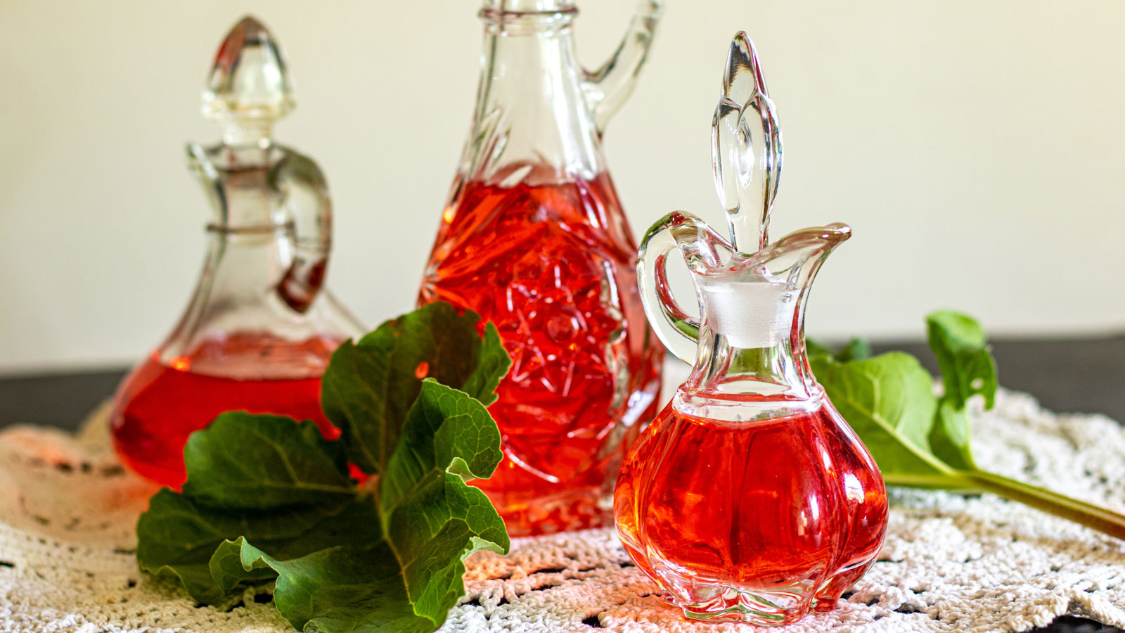 Rhubarb vinegar in cruets with rhubarb leaves.