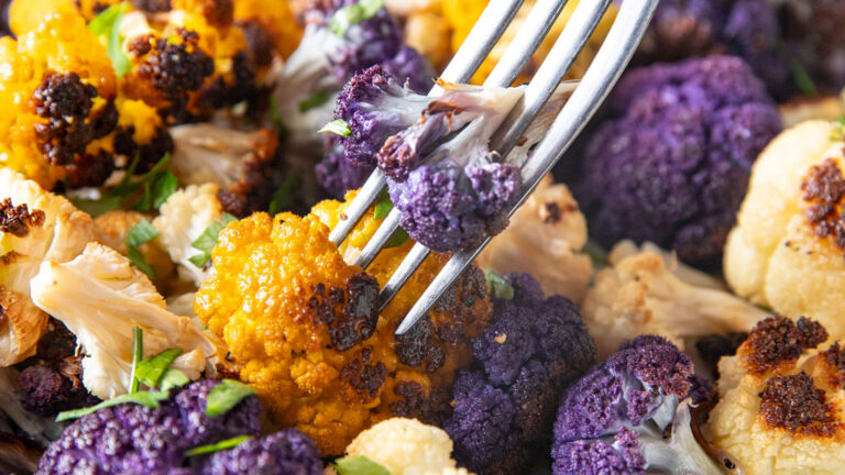Fork spearing a piece of purple cauliflower.