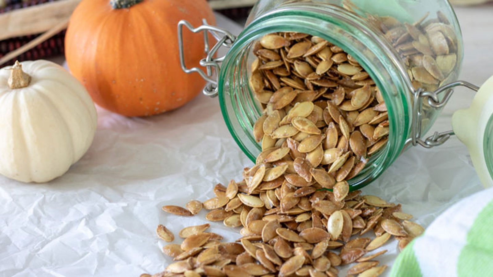 Roasted pumpkin seeds spilling out of canning jar.