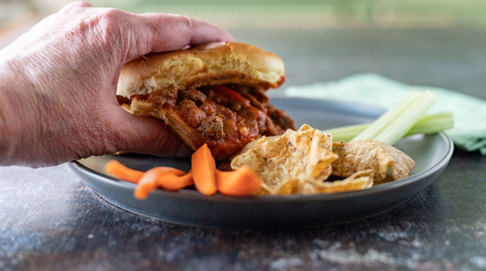 Hand grabbing sloppy joe sandwich.