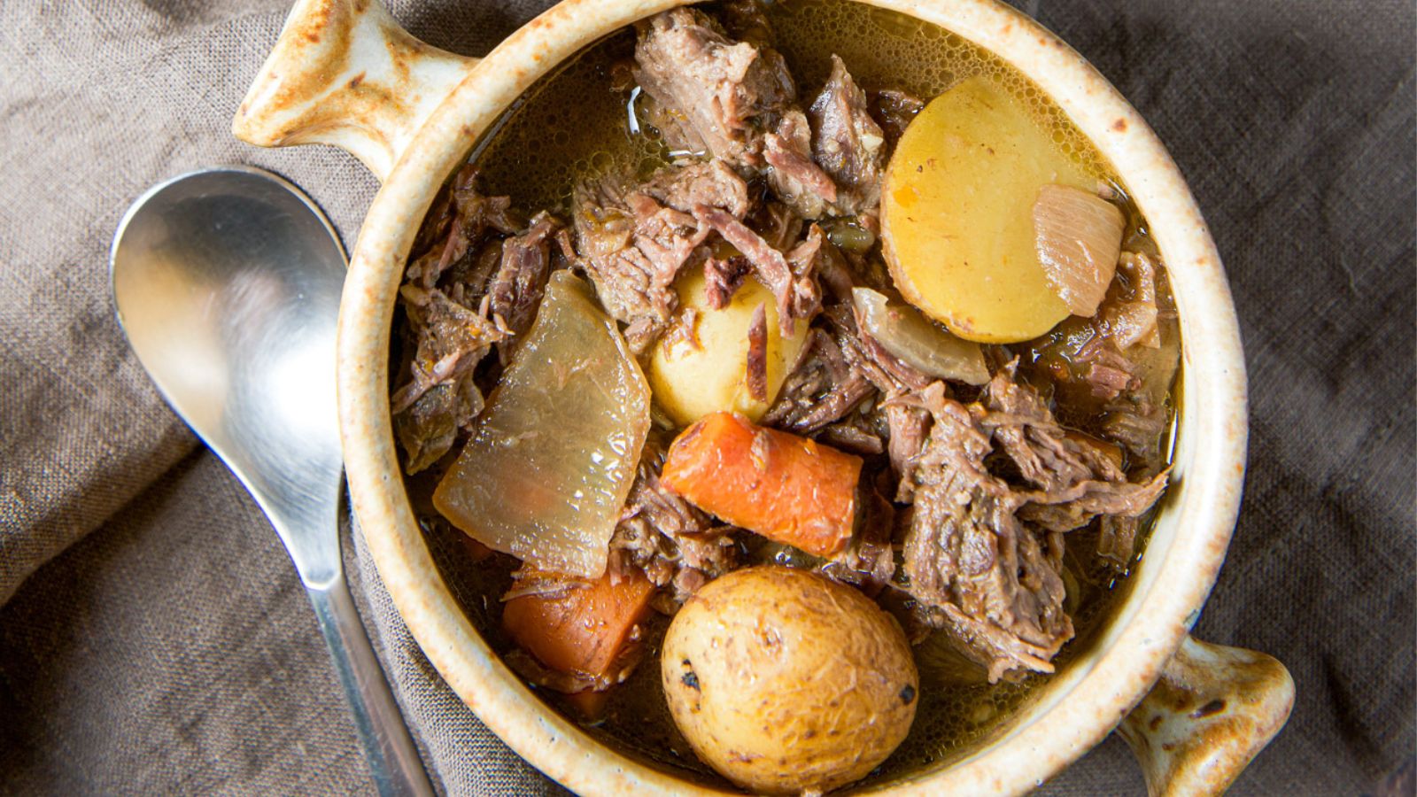 Chuck roast in a bowl with potatoes and carrots.