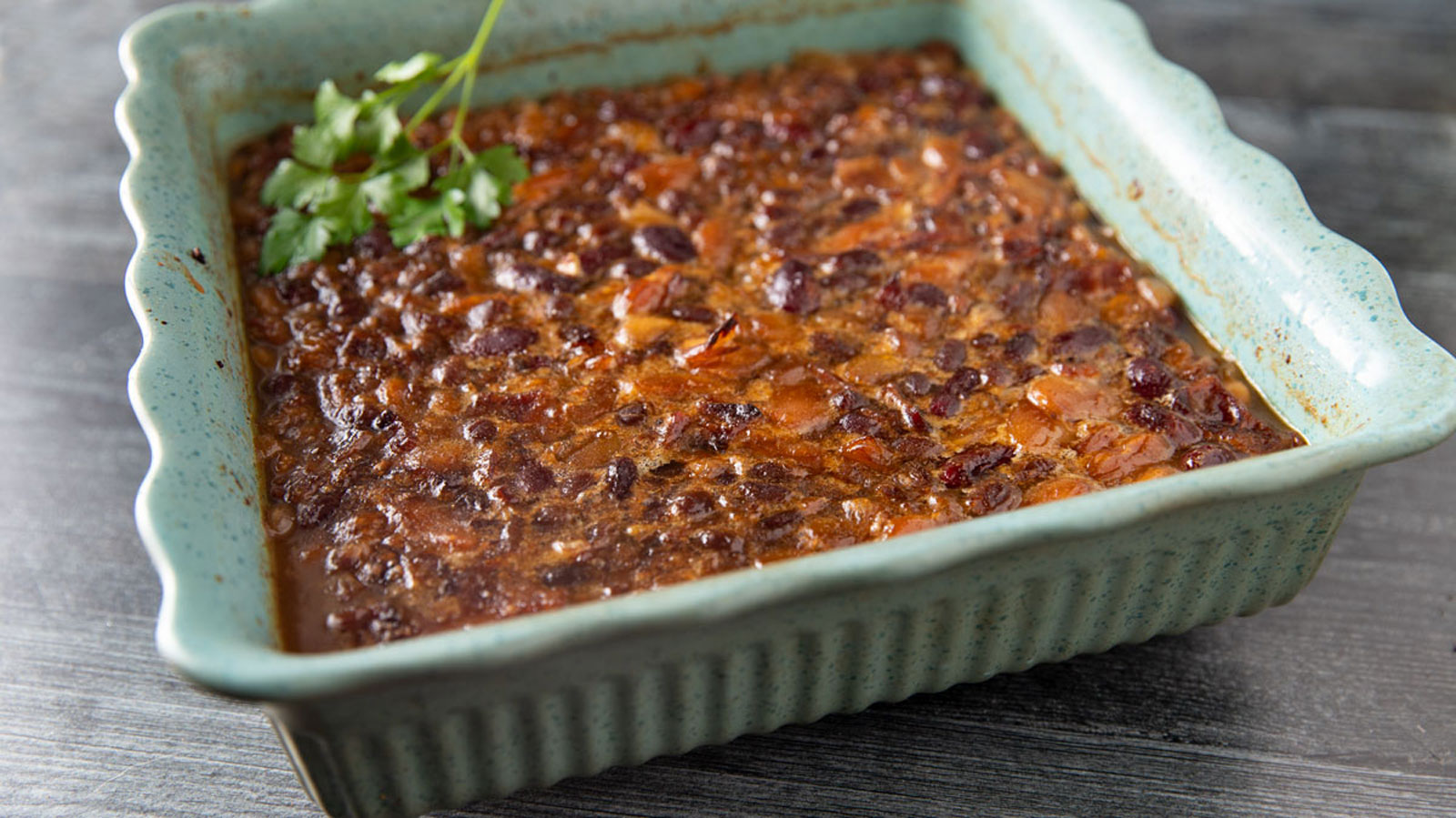 Smoked baked beans in a green baking dish.