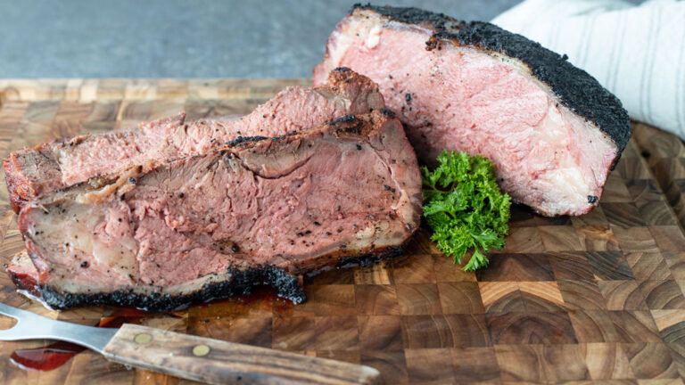Sliced smoked strip loin on wooden cutting board.