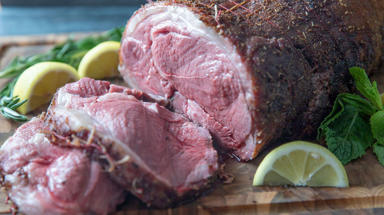 Sliced leg of lamb on wooden board.