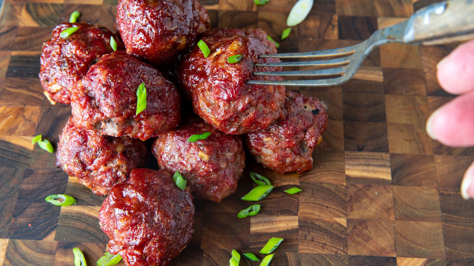 Pile of smoked meatballs on wooden board.
