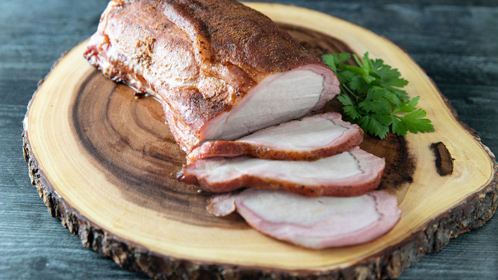 Smoked pork loin, sliced on a wood slab.