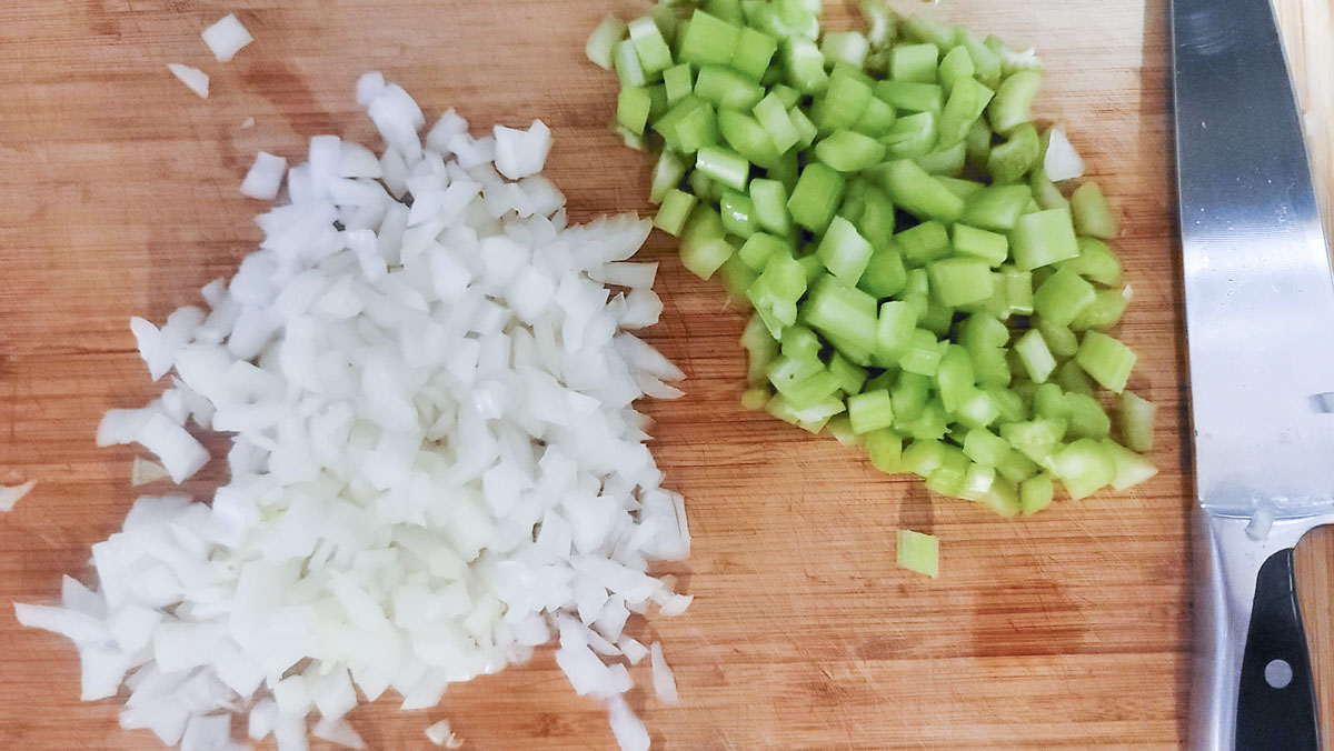 Chopped onion and celery on a cutting board.