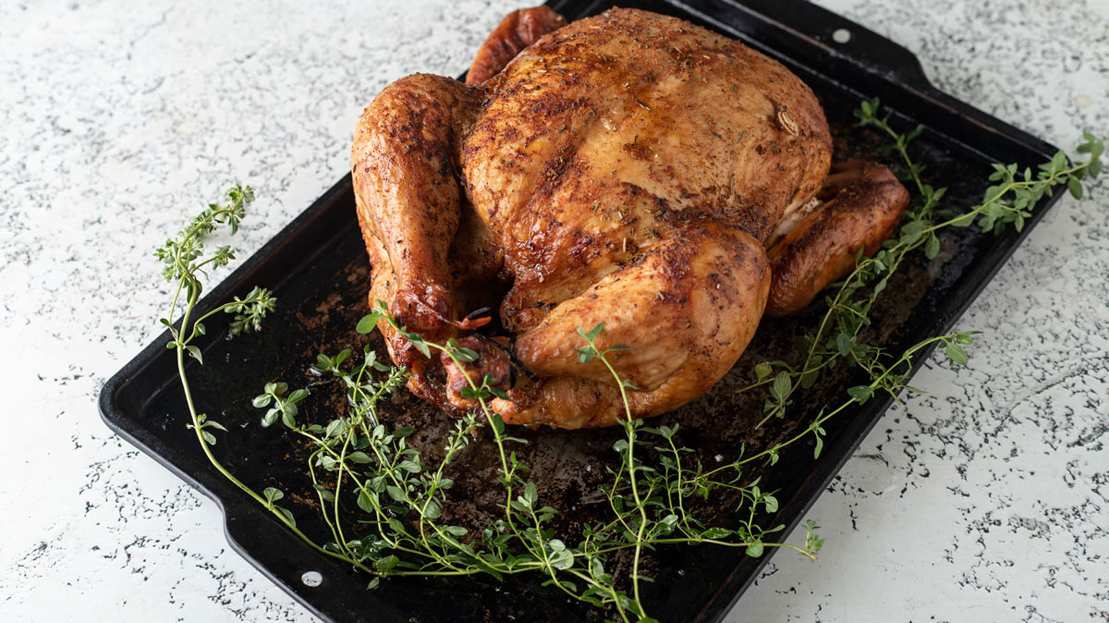 Whole golden brown chicken on an antique metal tray.