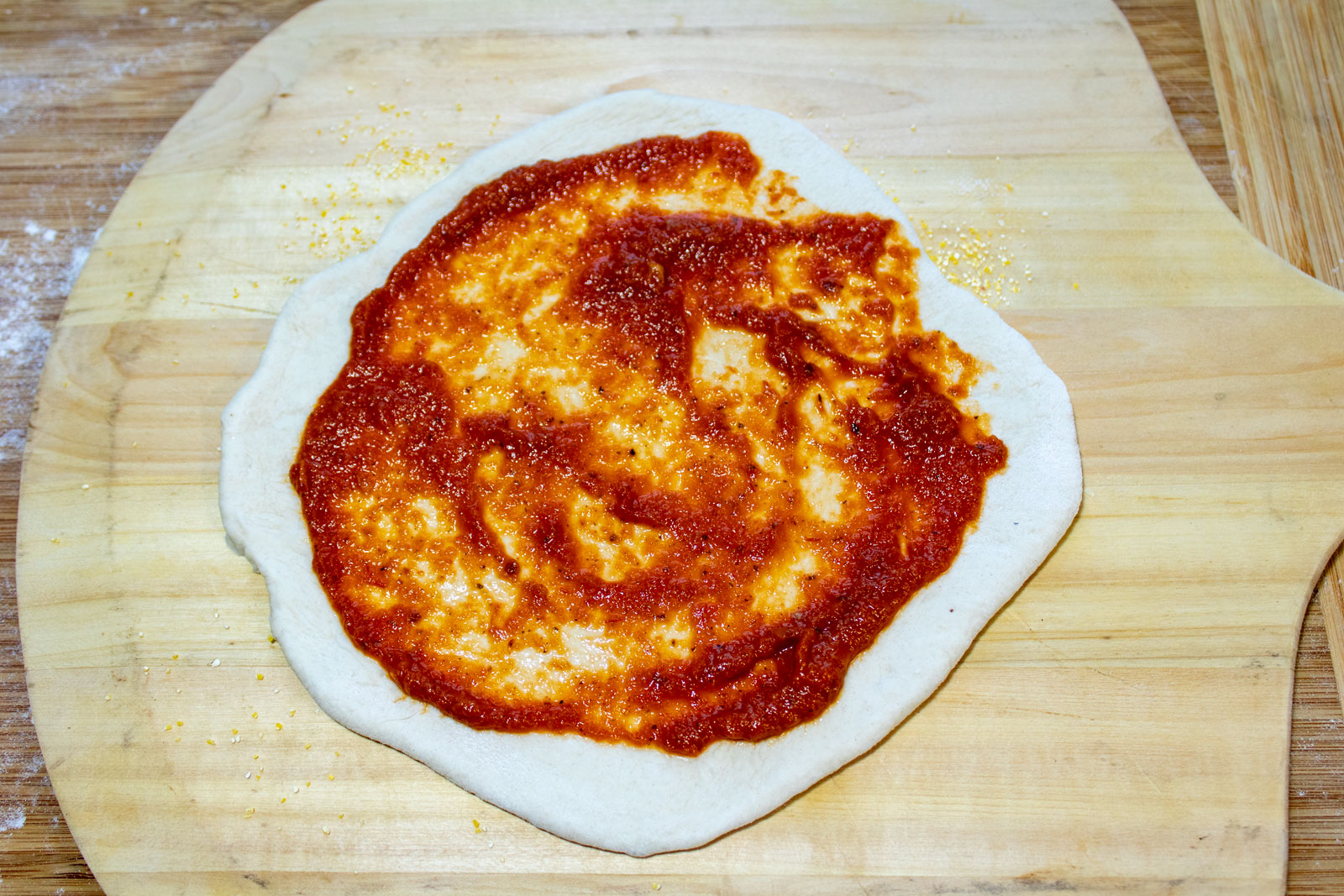 Sourdough pizza crust with tomato sauce on top.