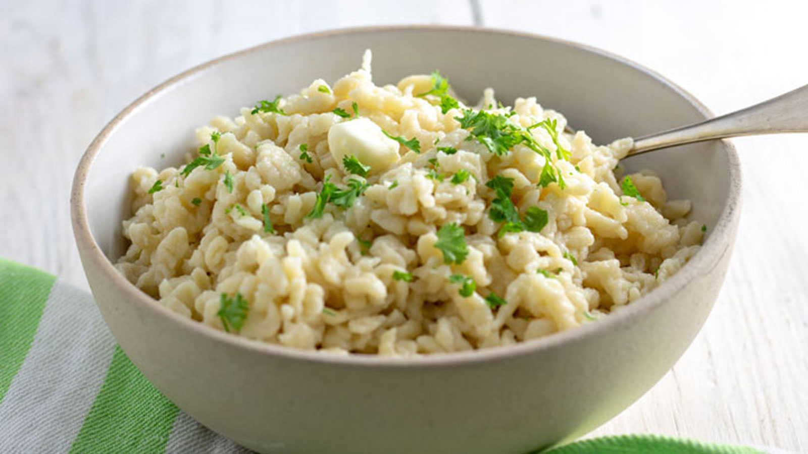 Beige bowl filled with homemade spaetzle garnished with parsley.