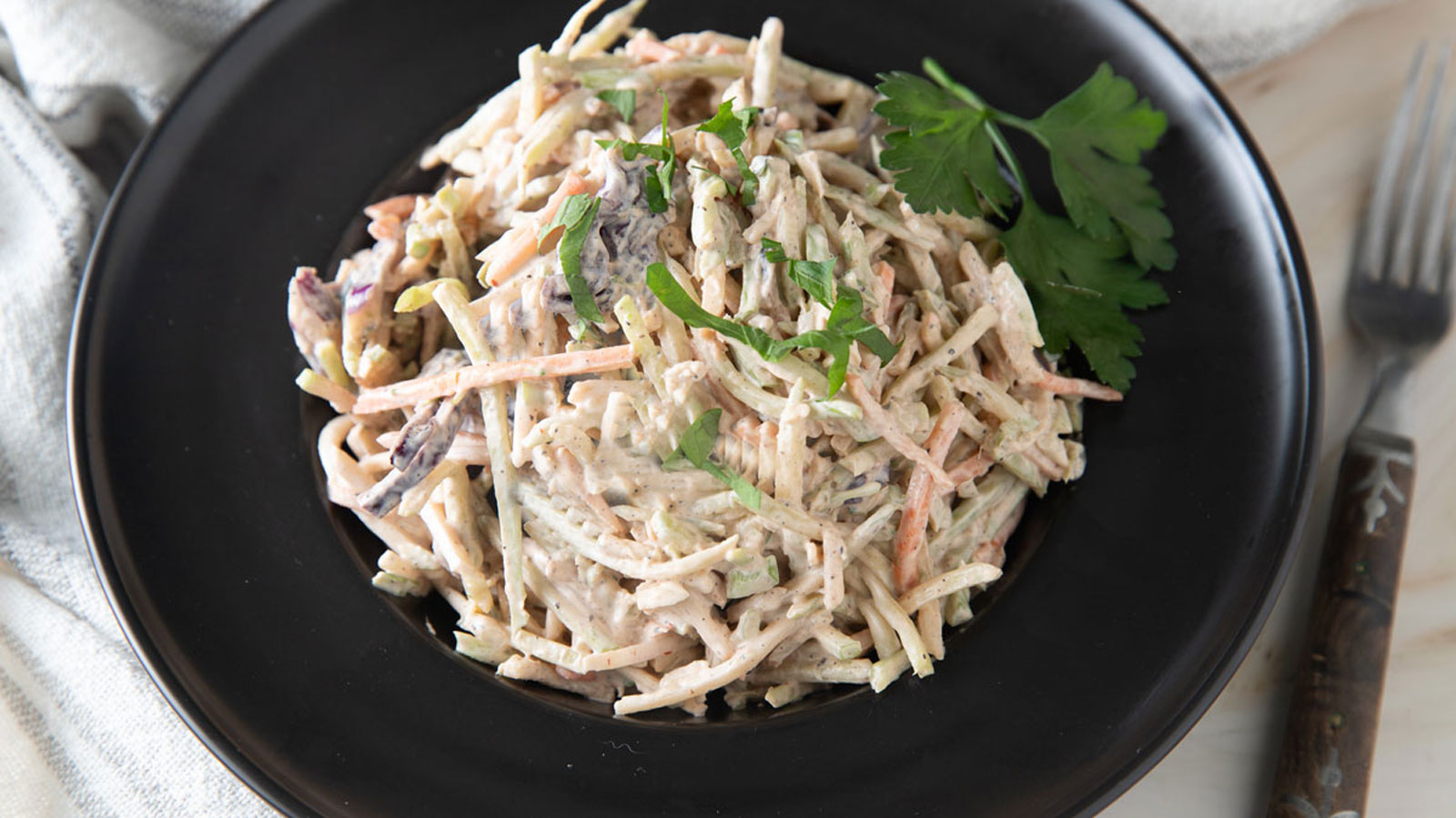 Spicy coleslaw in a black bowl with a large rim.