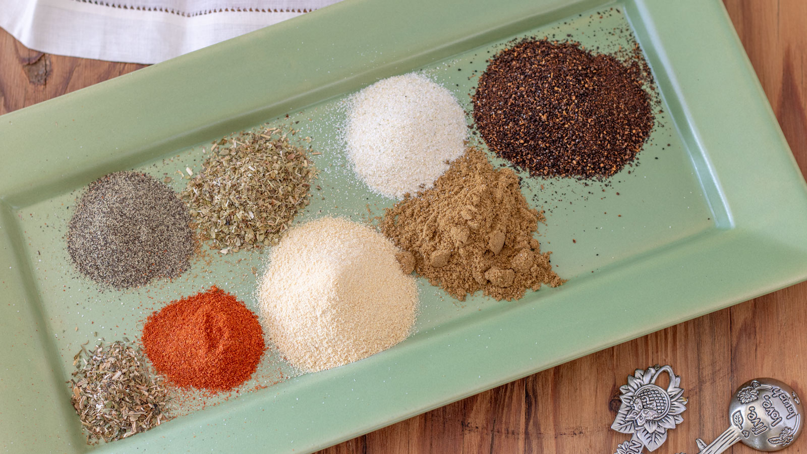 Spices for taco seasoning on green tray.