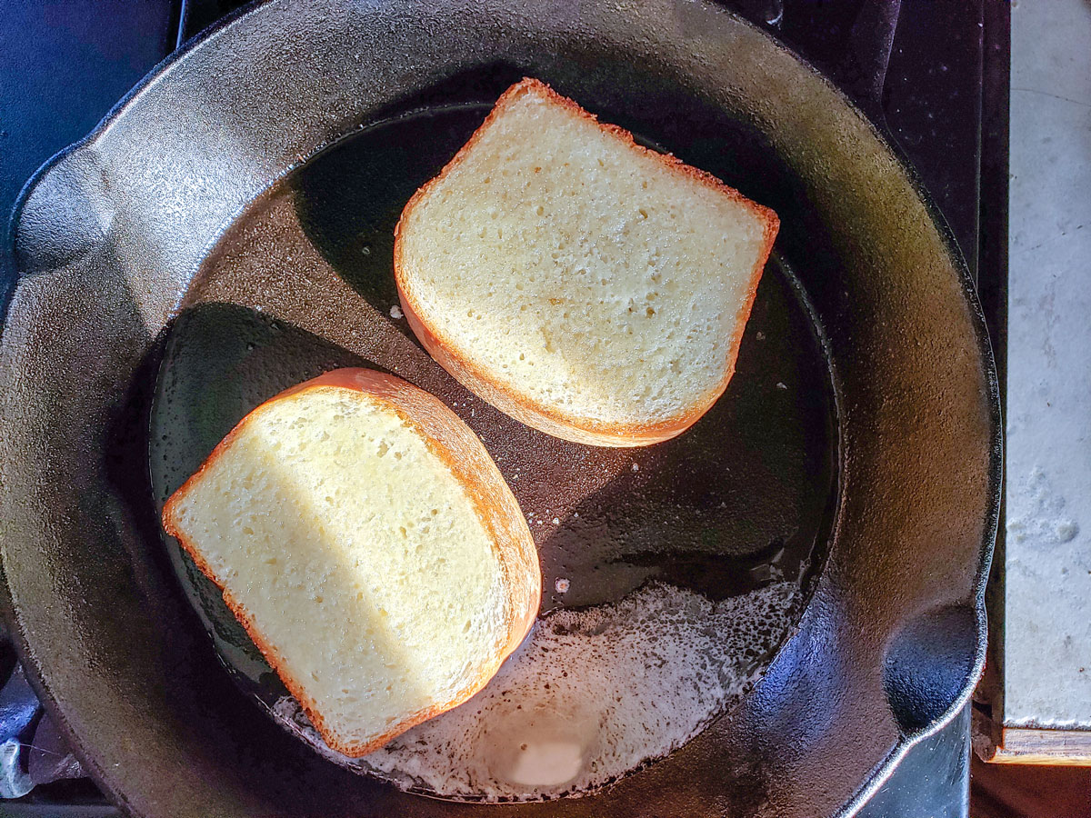 Two pieces of bread in a cast iron skillet.