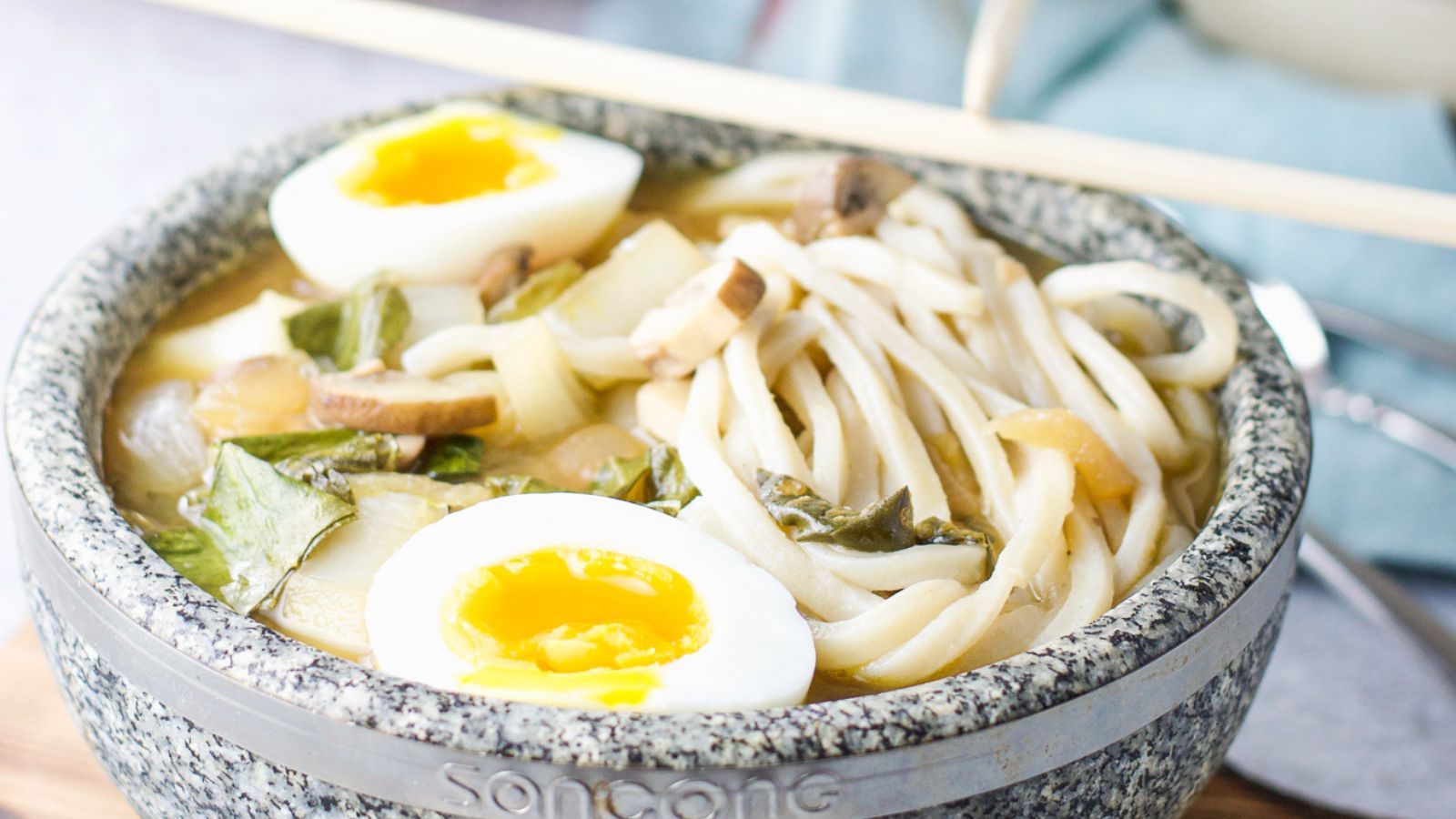 Soup in a gray bowl with soft boiled eggs.