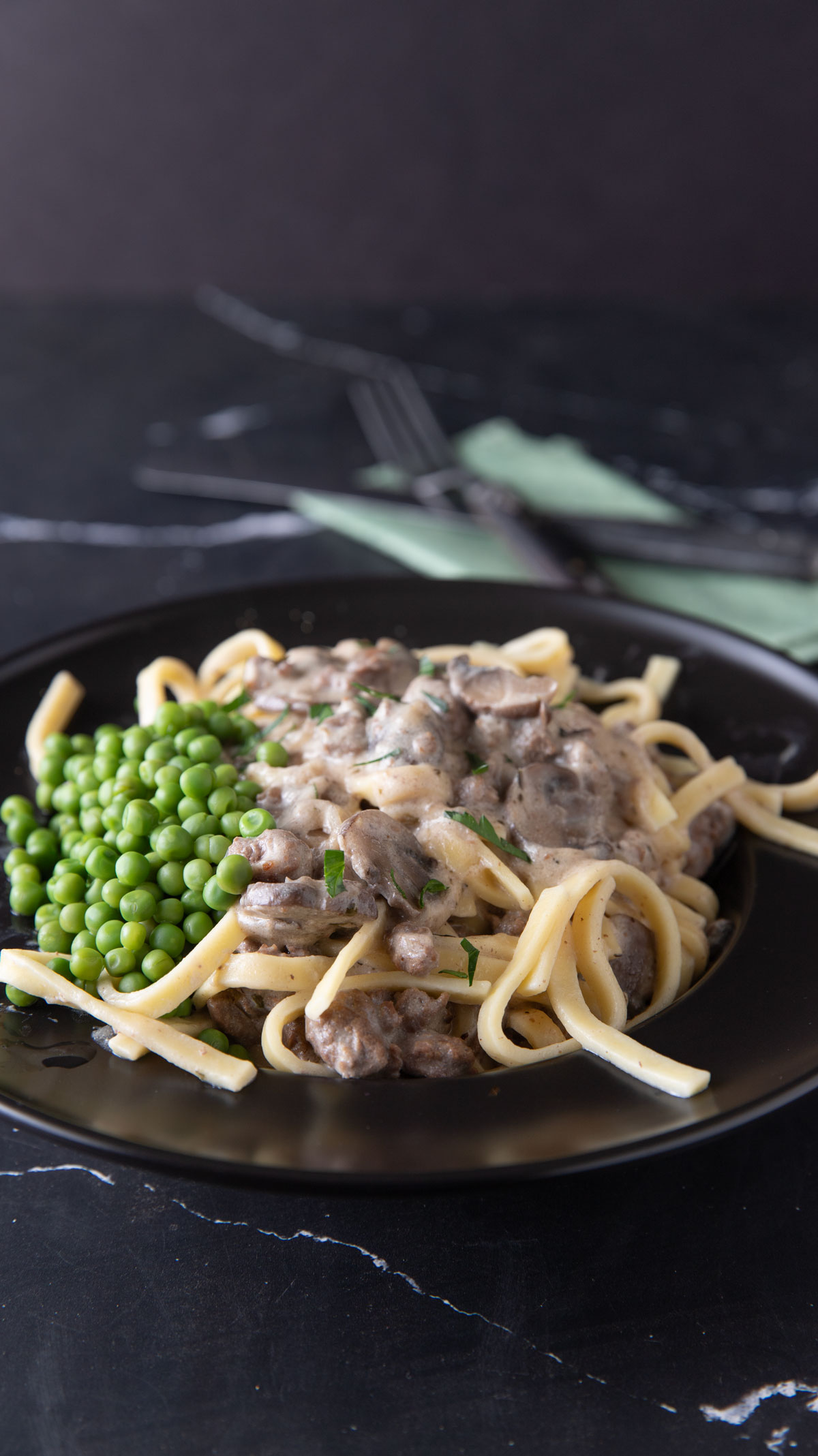 Stroganoff with peas in a black bowl.