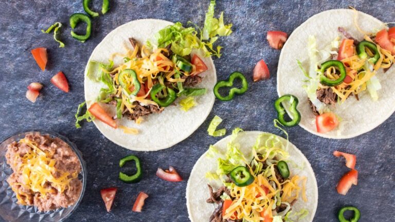Overhead photo of 3 venison tacos with toppings.