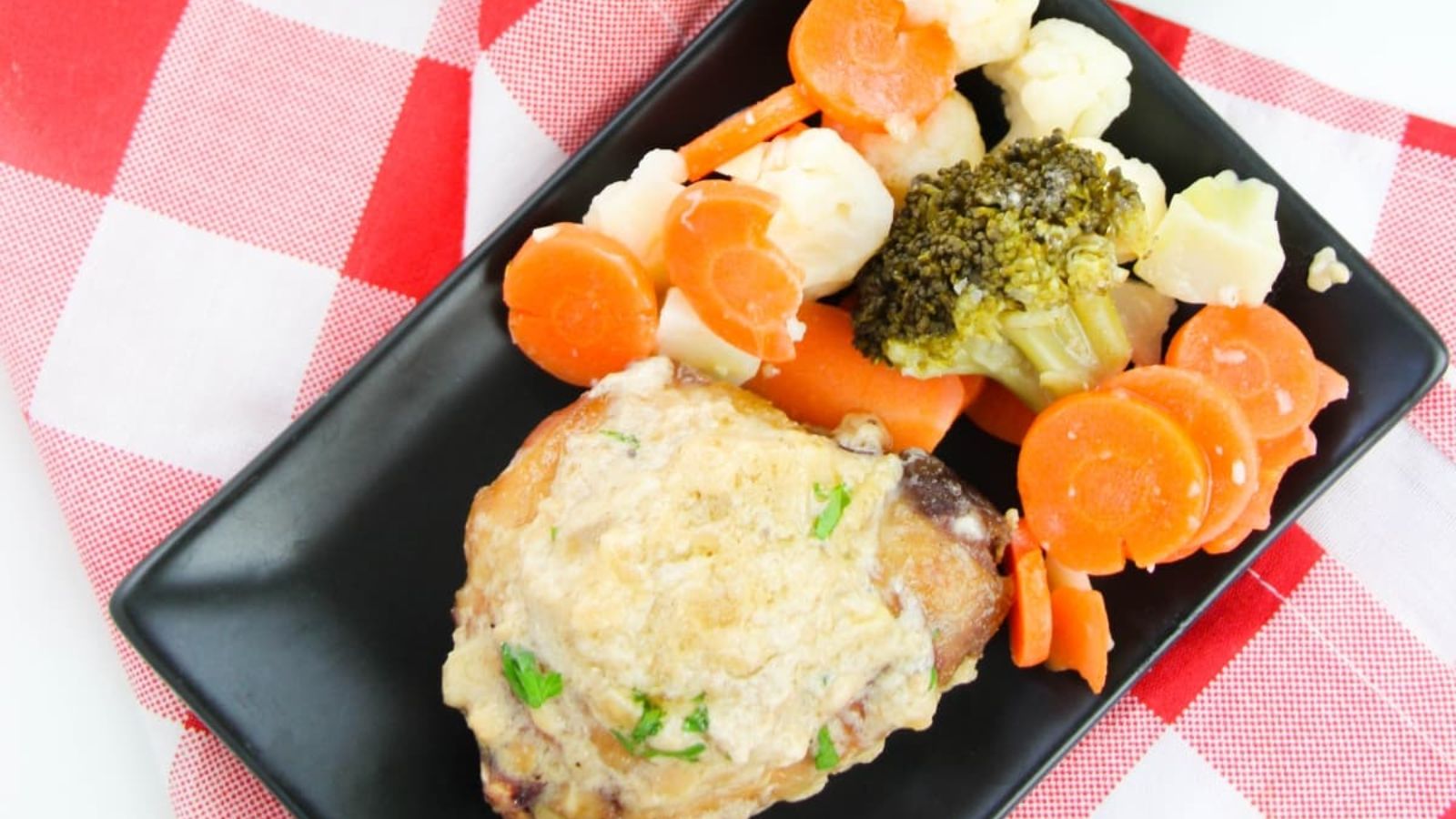 Lemon chicken on a plate with veggies on the side.