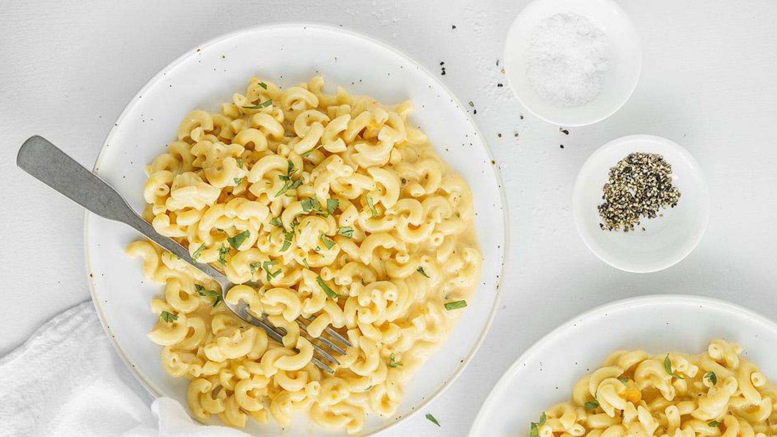 Macaroni and cheese on a white plate with parsley garnish.