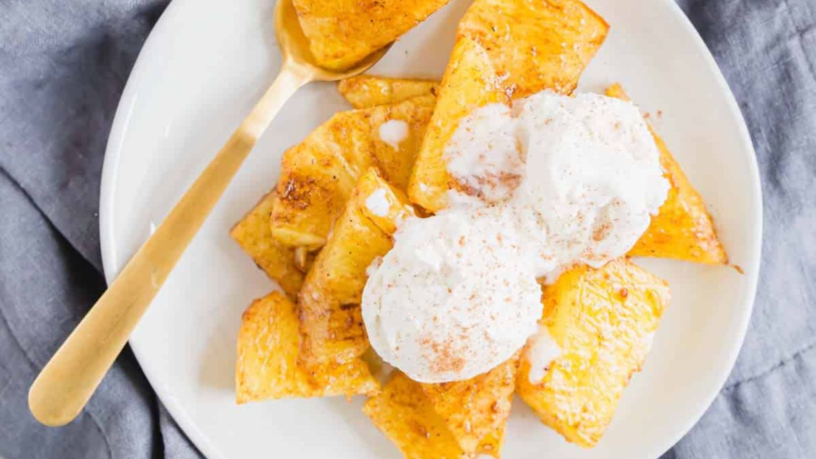Browned chunks of pineapple topped with vanilla ice cream.