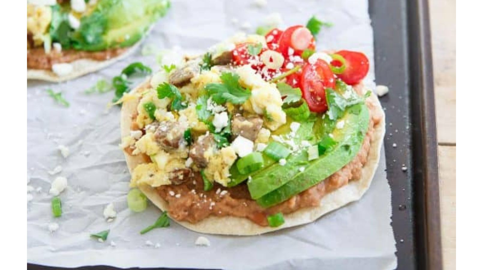 Corn tortilla topped with beans, eggs, cheese, adn avocado.