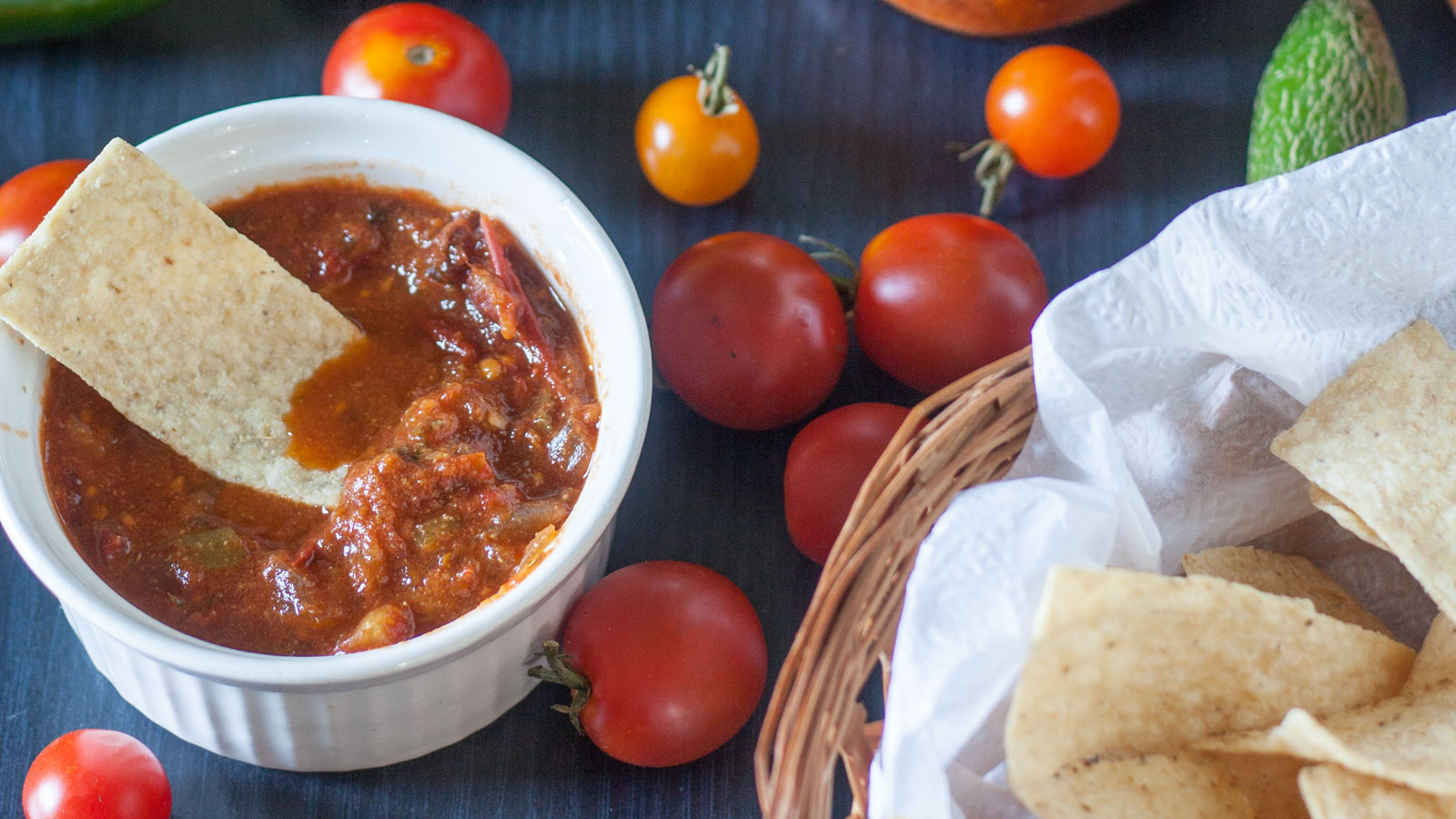 Small white bowl filled with salsa next to a bowl of chips.
