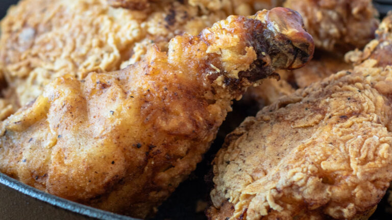 Close up of fried chicken in a cast iron skillet.