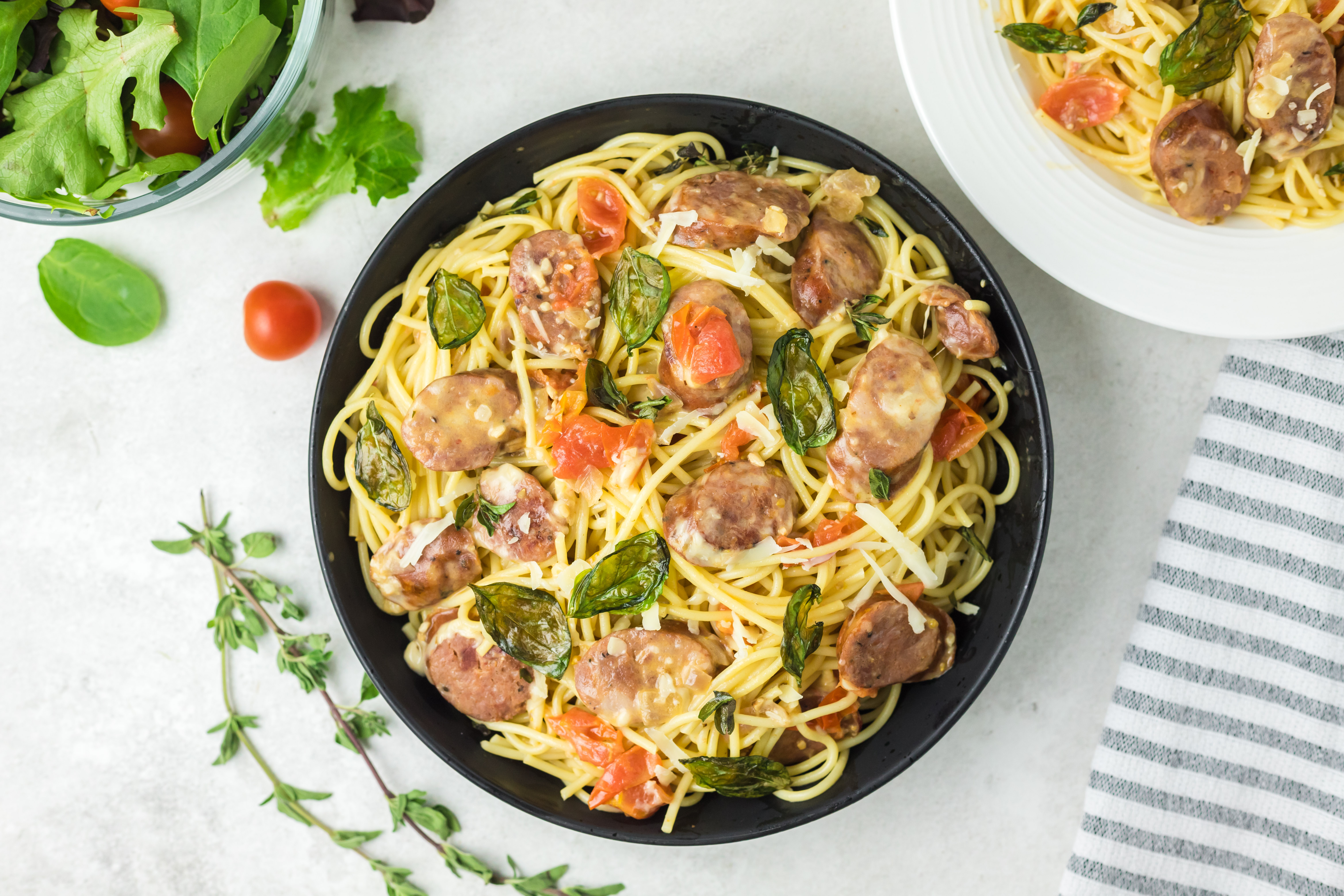 Chicken chorizo pasta with fried basil in a black bowl.