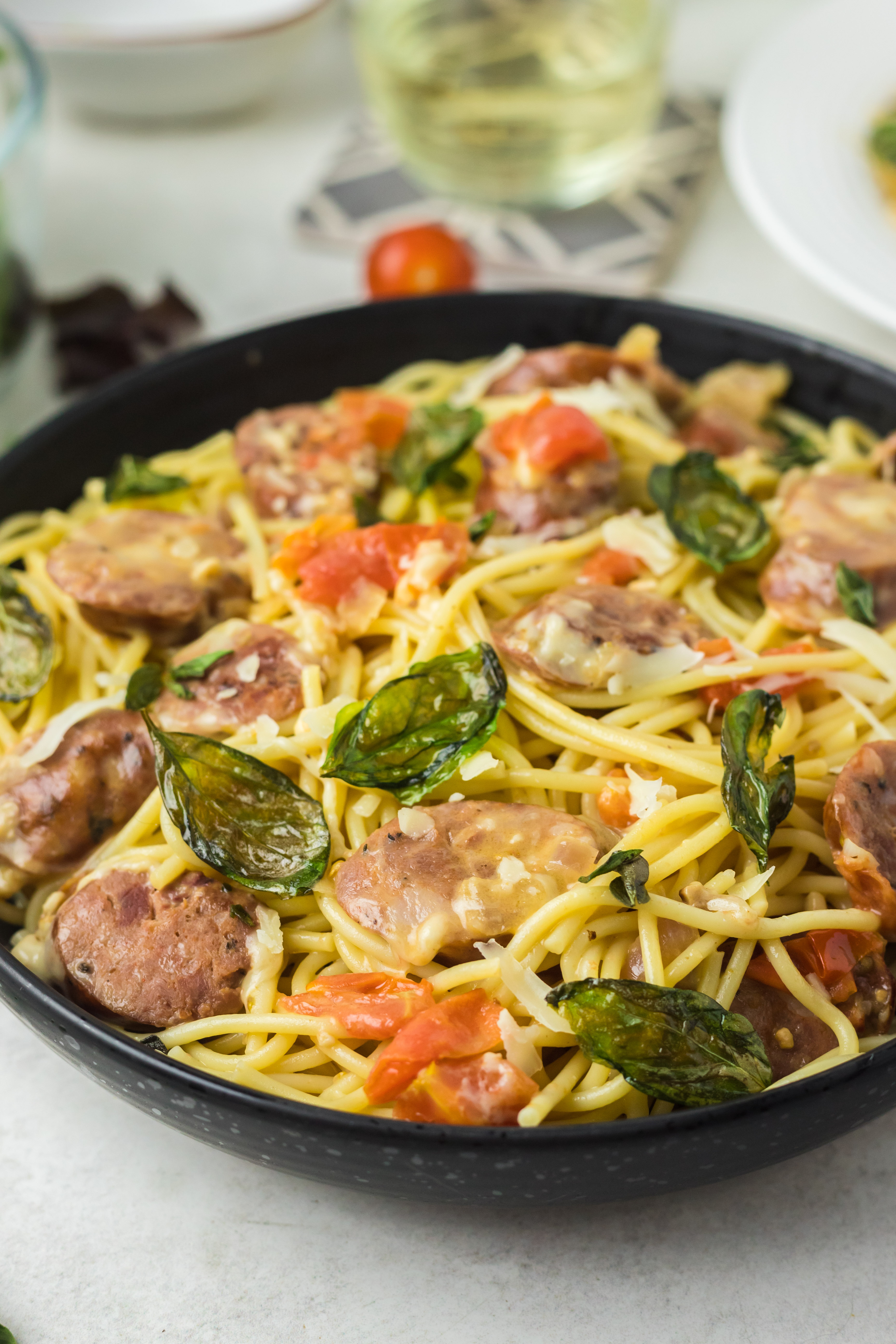 Colorful pasta dish in a black bowl.