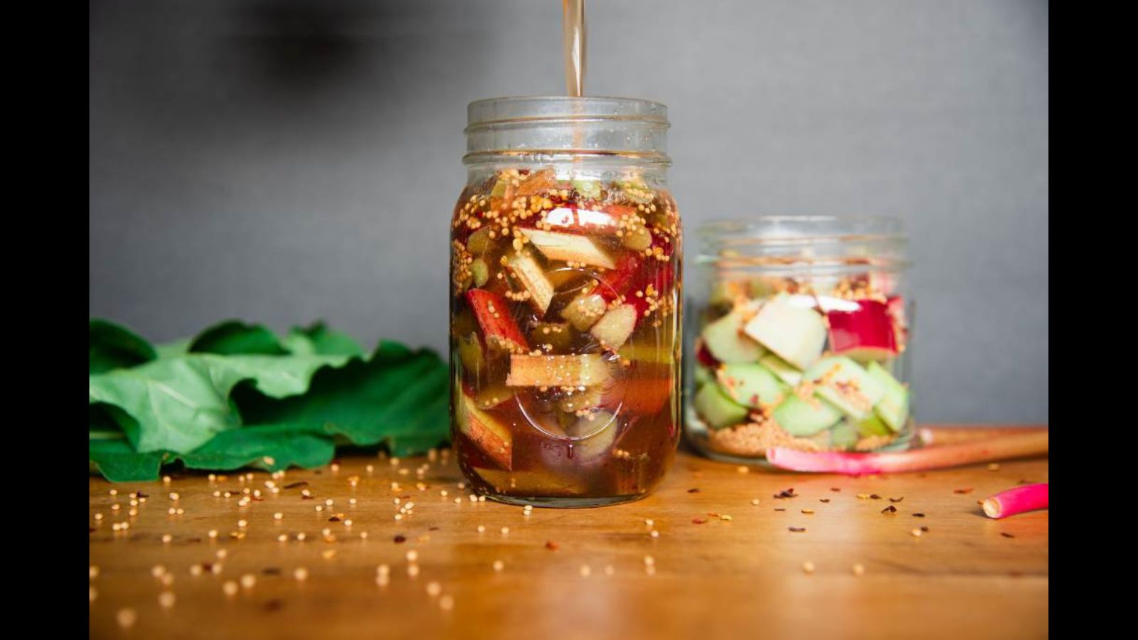 Jar of pickled rhubarb on a brown board.