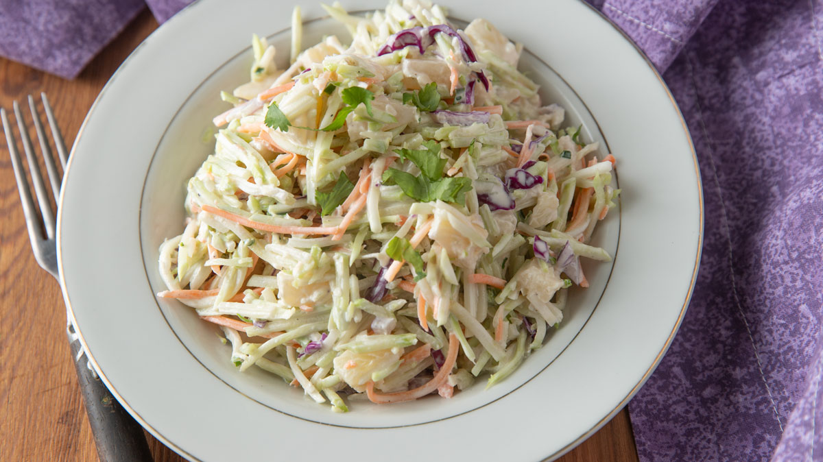 Pineapple coleslaw in a white bowl with a large rim.