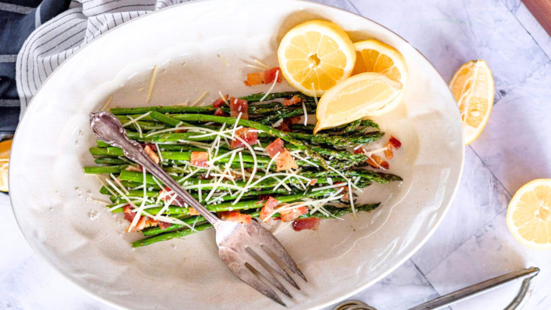 Smoked asparagus topped with grated Parmesan cheese on a white platter.