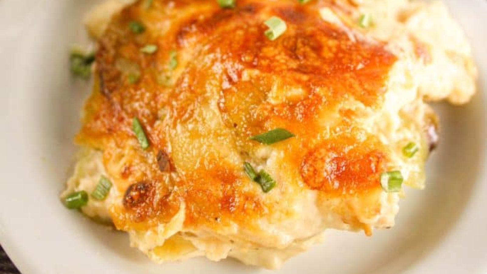 Spoonful of au Gratin potatoes on a white plate.