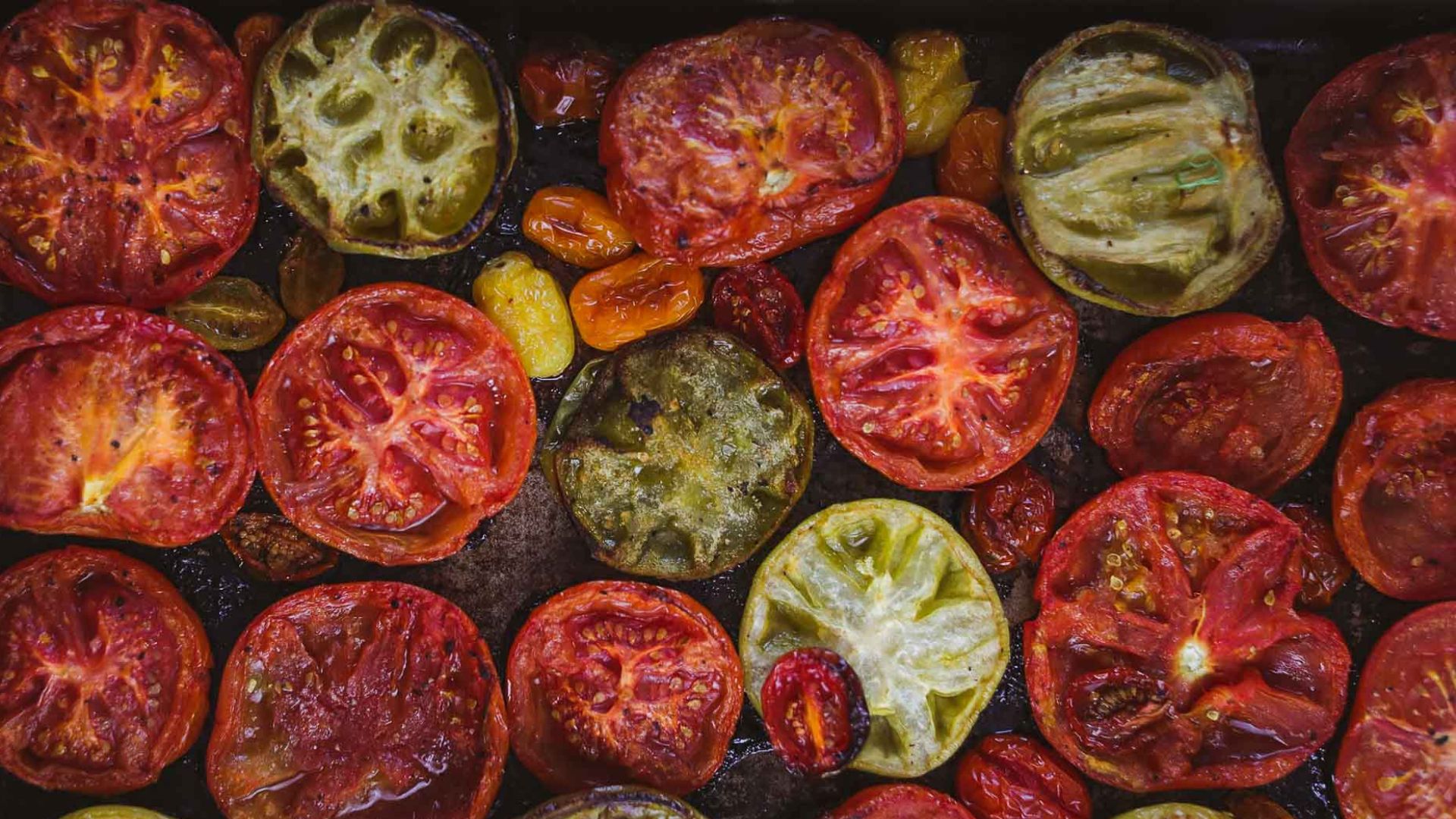 Smoked red and green tomatoes on a baking sheet.