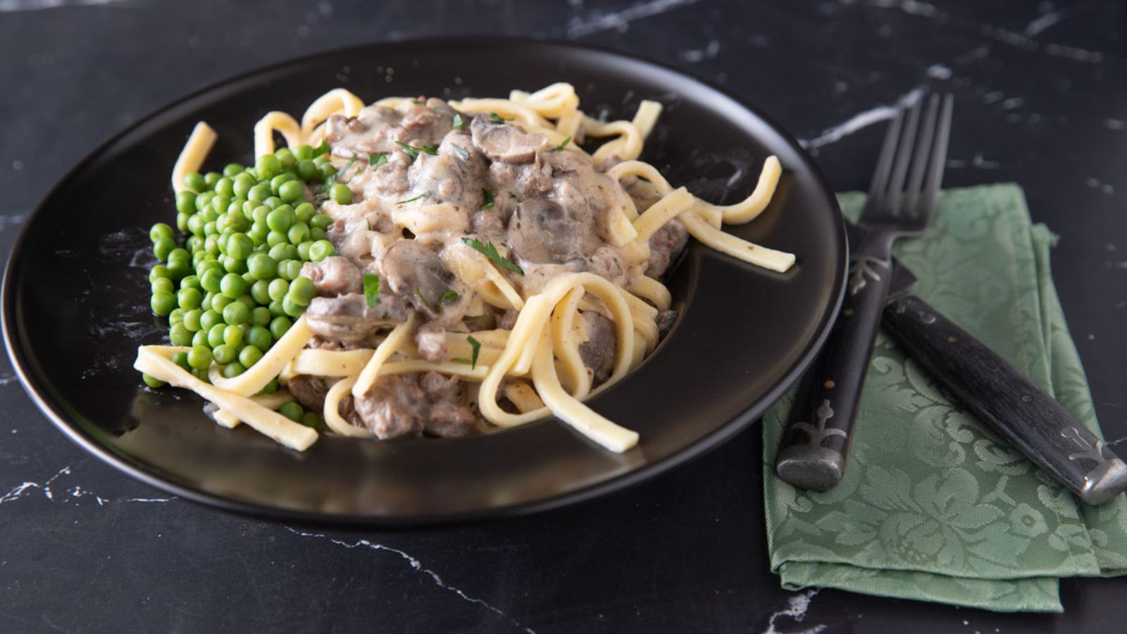Stroganoff with peas in a black bowl.