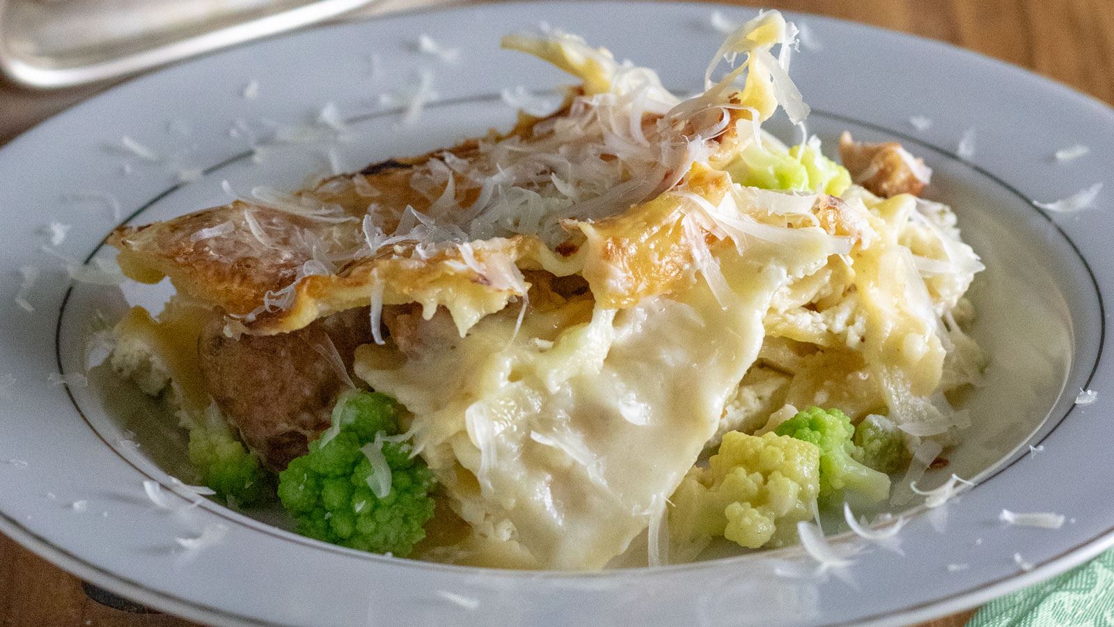 Slice of white lasagna in a white bowl with Romanesco.