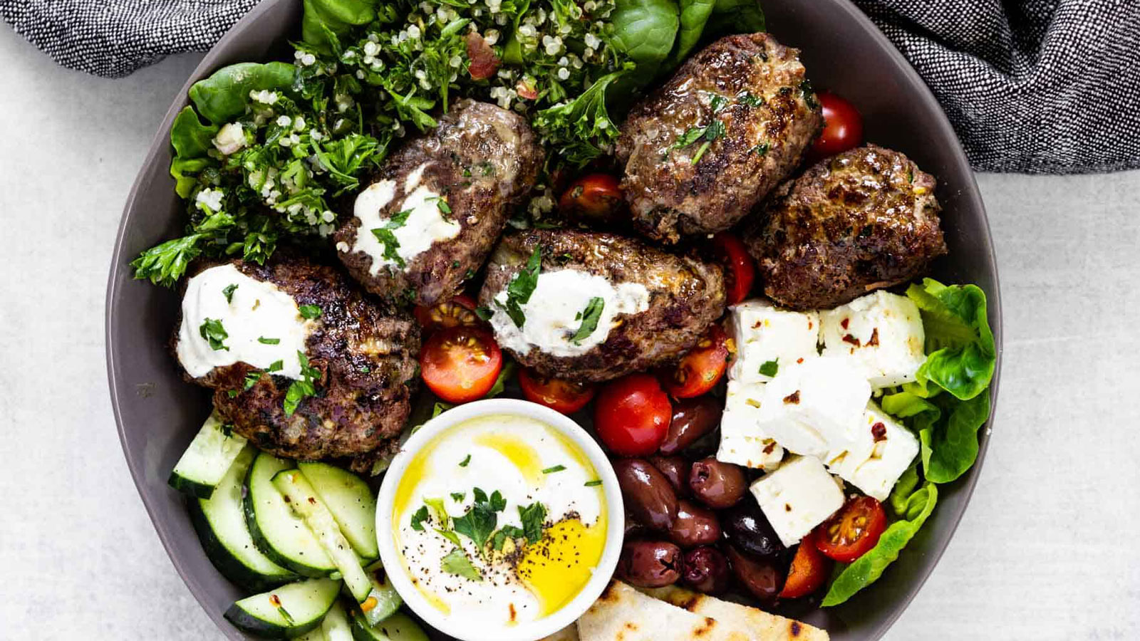 Beef koftas with yogurt sauce on a plate.