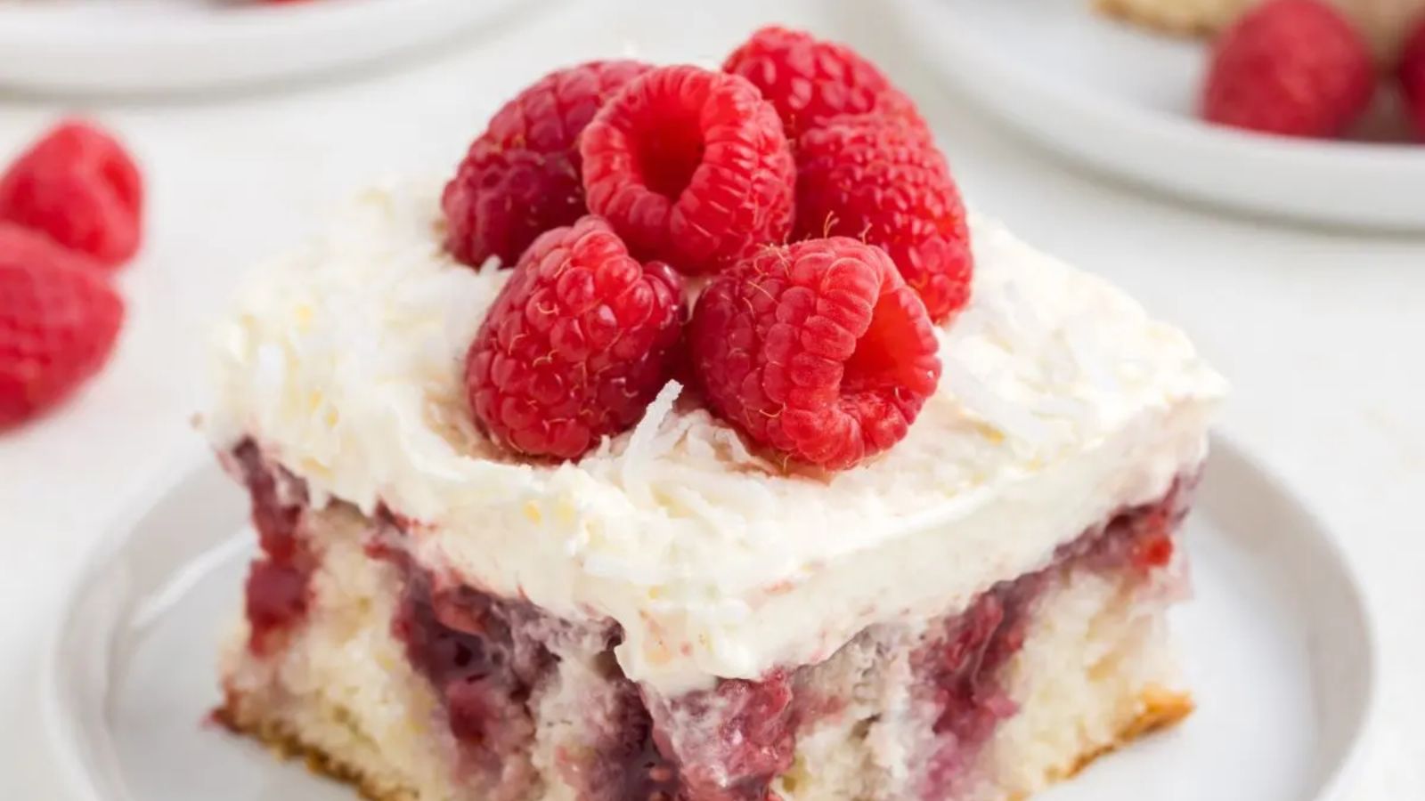 Raspberry poke cake with whole raspberries on top.