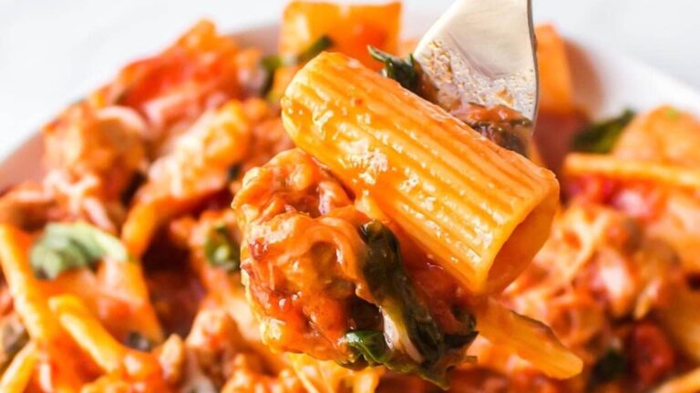 Saucy covered rigatoni pasta with a white bowl.