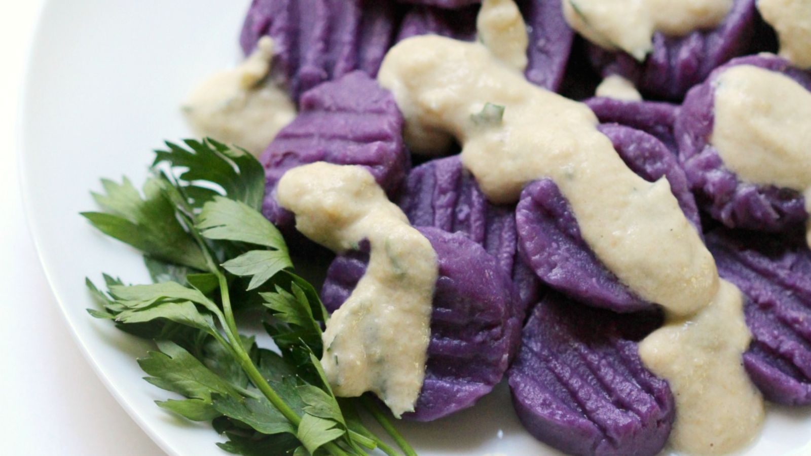 Purple Sweet Potato Gnocchi With Tahini Parsley Sauce on a plate. 