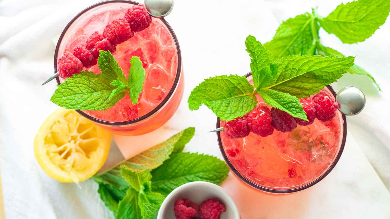 Vodka in glasses with raspberries and mint on top.
