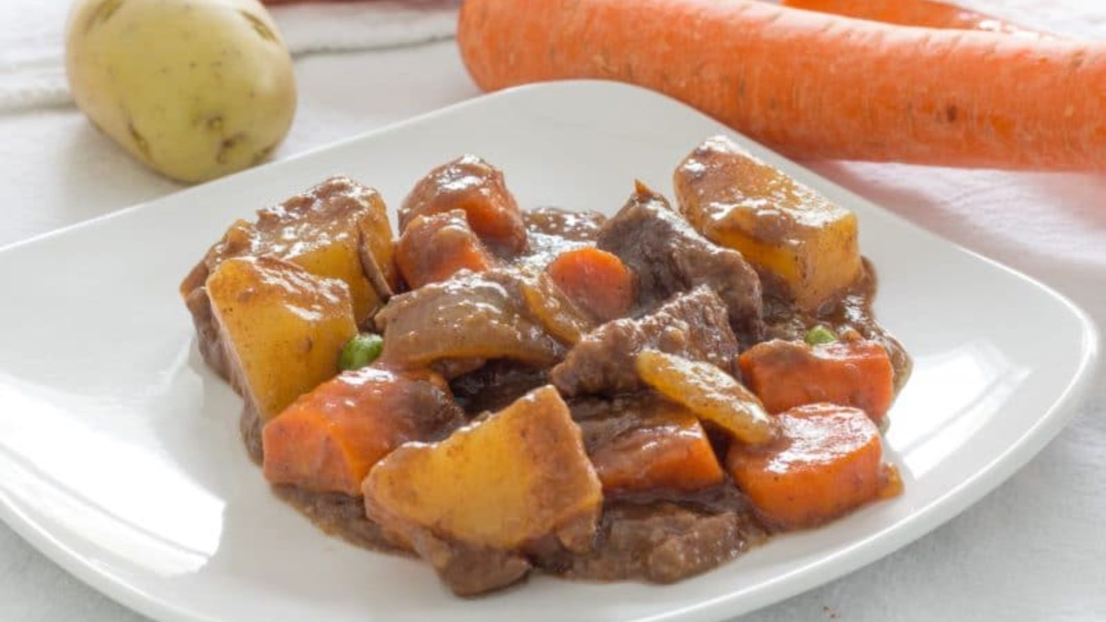 Beef stew on a plate with carrots and potatoes.